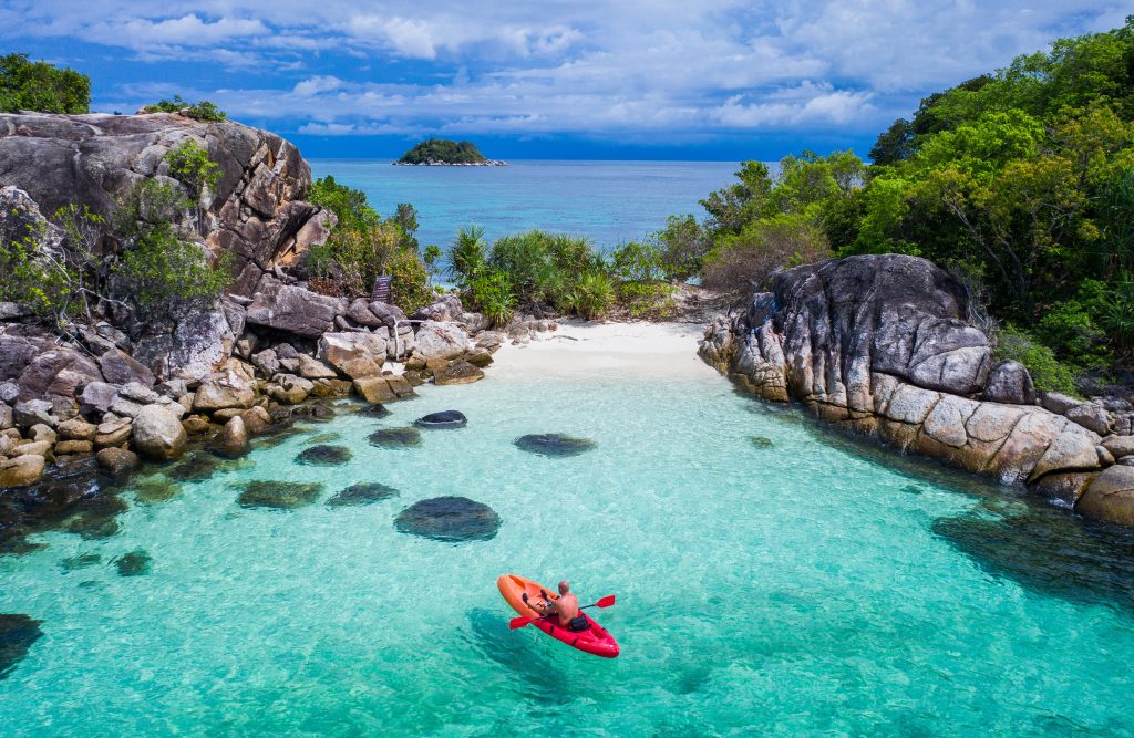 Man kayaking in crystal clear water near Koh Lipe island in Thailand.