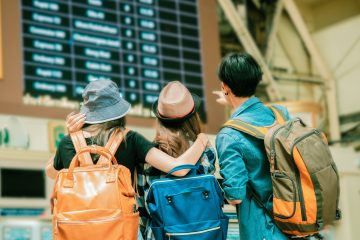 Three travellers looking at time board for traveling.